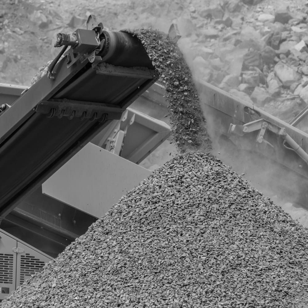 A conveyor belt carriers crushed stone and dumps it into a large pile.
