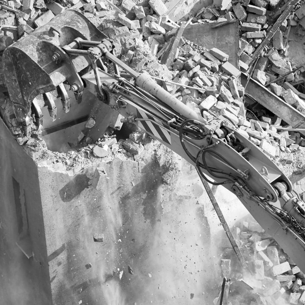 An excavation machines works at knocking down a structural wall.