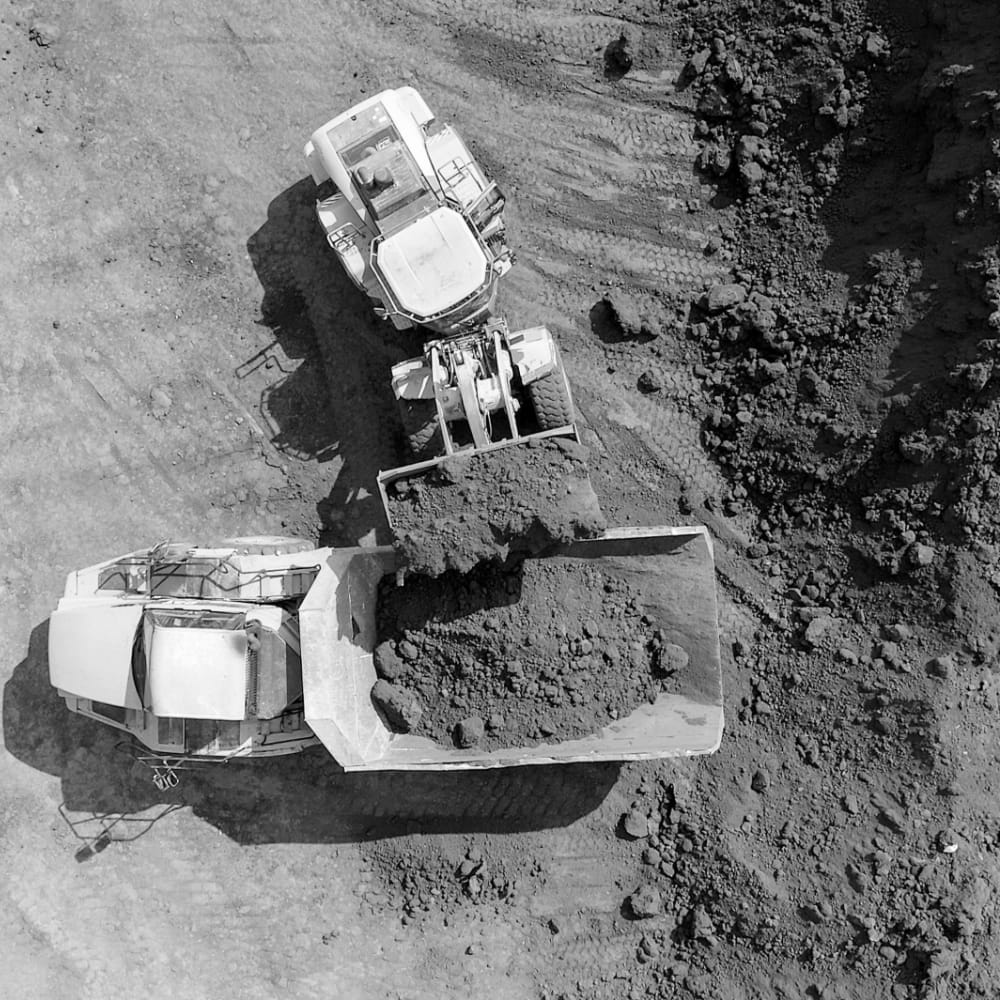A loader dumps dirt into the bed of a dump truck.
