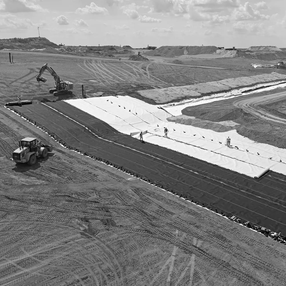 Construction equipment and crews lay the foundation for a landfill site.